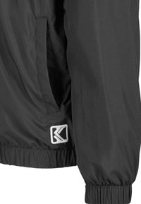 Black lightweight jacket featuring a elasticized cuff, side pocket, and a rectangular logo patch in white on the lower left side.