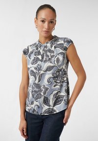 Seidenbluse ohne Ärmel in Hellblau mit marineblauen Blumenmustern. Verfügt über einen gerafften Ausschnitt und einen lässigen Schnitt. Strukturierte Stoffoberfläche.