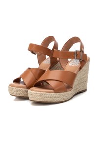 Sandali wedge in pelle marrone con cinturini incrociati e una cinghia alla caviglia regolabile. Presentano una piattaforma in juta intrecciata e una soletta liscia.