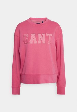Sweat-shirt rose à col rond avec manches longues et "GANT" en grandes lettres cousues sur la poitrine, présenté sur un fond uni.
