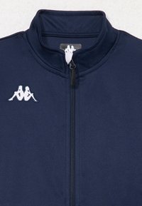 Marine blauwe ritsjack met een hoge kraag, voorzien van een wit Kappa-logo aan de linkerkant en een soepel, lichtgewicht stofontwerp.