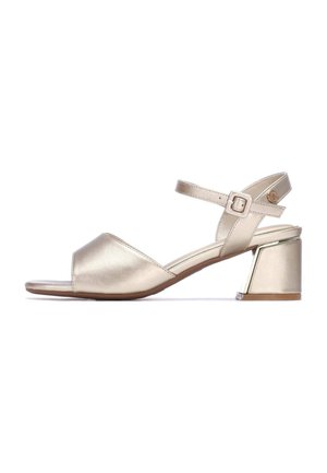 Sandalias de tacón dorado metálico con diseño de punta abierta. Cuentan con una correa ajustable en el tobillo y un tacón grueso con un detalle transparente.