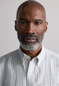 Collared, button-up shirt with light gray and blue stripes. Made of a textured fabric, featuring a relaxed fit and a classic look.