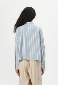 Blauw gestreepte overhemd met lange mouwen en een cropped ontwerp, gemaakt van een lichte stof, met een kraag en details op de manchetten.