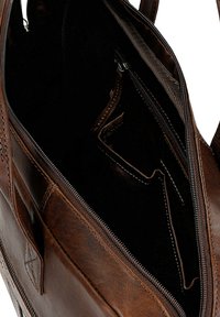 Brown leather satchel with a zippered opening. Interior features dark lining, multiple compartments, and a small zipper pocket.
