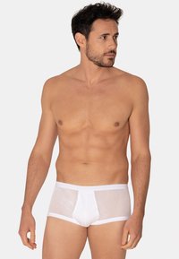 Slip en maille blanche avec ceinture solide, dotée d'une poche à l'avant et d'un design ajusté. Le tissu a une texture transparente et respirante.