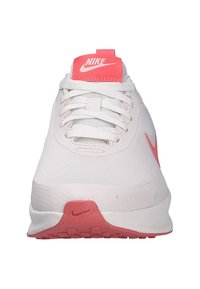 Zapatilla de running de Nike con una parte superior de malla blanca, acentos en rosa brillante en la lengüeta y el logo, suelas texturizadas y un diseño de punta redondeada.