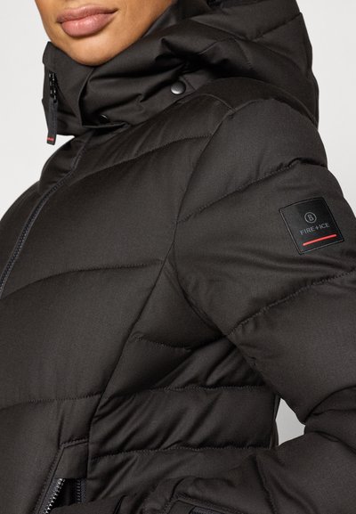 Μαύρο μπουφάν puffer με ψηλό γιακά, κλείσιμο με φερμουάρ και διαγώνια ραφή. Διαθέτει λογότυπο με κόκκινα στοιχεία στο μανίκι.