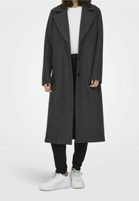 Grijze wollen jas met een lang, recht ontwerp, brede revers en twee knopen. Gecombineerd met zwarte jeans en witte sneakers.