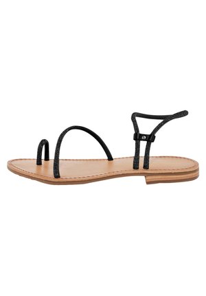 Sandalo nero con cinturini sottili, suola piatta marrone chiaro, design minimalista e cuciture decorative lungo i bordi.