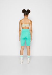 Calções atléticos verde menta com uma cintura alta e uma textura suave, combinados com um cropped com padrão floral. Meias brancas com riscas teal.