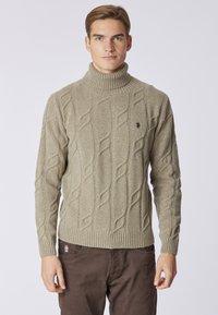 Maglione beige a collo alto in maglia rasata con polsini e orlo a coste. Presenta un motivo testurizzato e un piccolo logo sul petto.