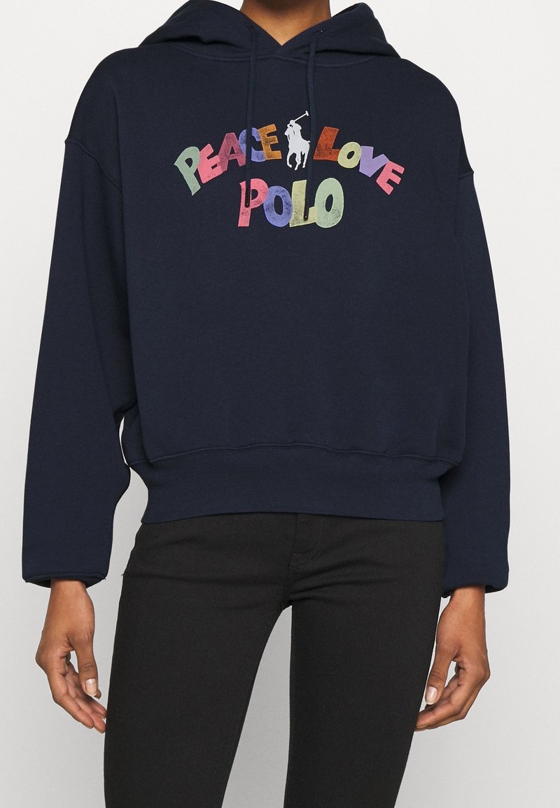 Felpa blu navy con vestibilità ampia, caratterizzata da un testo colorato "PACE AMORE POLO" e un piccolo logo di un cavallo. Tessuto morbido e polsini a coste.