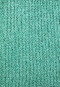 Türkisfarbener Strickstoff mit einem strukturierten, gerippten Muster. Das Material wirkt weich und weist unterschiedliche Fadendicken für eine tiefe Struktur auf.