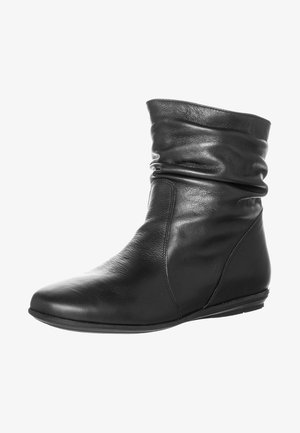 Bottine noire en cuir avec tige souple et décontractée et semelle plate, conçue pour un usage décontracté.