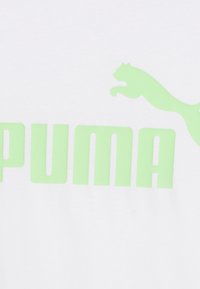 Bílý bavlněný tričko s velkým, světle zeleným textem "PUMA" a zeleným logem skákajícího pumy nad textem. Hladká textura.