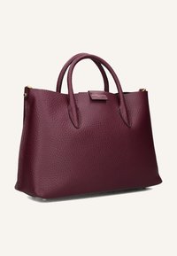Borsa a mano in pelle testurizzata bordeaux scuro con doppi manici rotondi e hardware dorato discreto su sfondo chiaro.