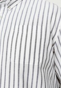 White button-up shirt made of fabric with gray vertical stripes, featuring a chest pocket and a classic collar design.