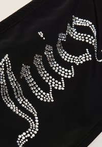 Schwarzer Stoff mit glatter Textur, der ein Design von angeordneten silbernen Strasssteinen in einem fließenden Muster zeigt. Keine weiteren Details sichtbar.