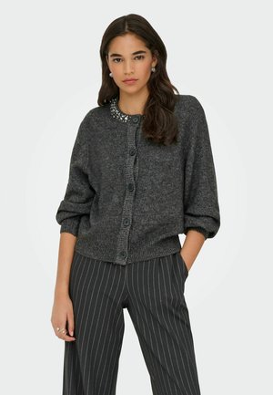 Ciemnoszara dziergana kardigan z okrągłym, ozdobnym dekoltem, długimi bufkami i zapinany na guziki, zestawiony z spodniami w prążki.