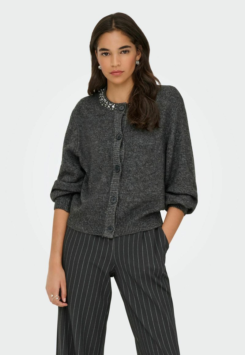 Tumehall villane kampsun, millel on ümmargune kaunistatud kaelus, pikad puffvarrukad ja nööpidega eesmine osa, kombineerituna triibuliste pükstega.