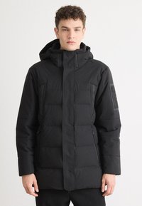 Sort isoleret jakke med hætte, der har en quilted tekstur, lynlåslommer og lige snit. Glat stof med minimal detaljer.