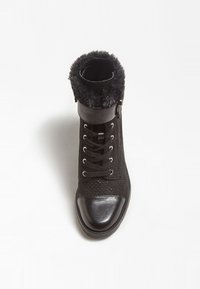 Bottine noire avec un col en fausse fourrure douce, tige en daim texturé, perforations et un embout en cuir verni noir. Elle dispose de lacets et d'une boucle.