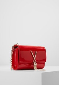 Borsa a tracolla in pelle lucida rossa con design a ribalta, tracolla in catena dorata e un grande dettaglio con logo 'V' oro sul davanti.