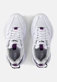 White athletic shoes with mesh material, purple accents, textured soles, and prominent laces. Brand logo displayed on the tongue and heel.