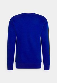 Sudadera azul de tela suave con cuello redondo, mangas largas, puños acanalados y un detalle negro en una manga.
