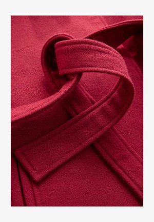 Burgundy ullkappa med en mjuk textur, med ett brett bälte och överlappande tyg, som framhäver rena linjer och en strukturerad design.