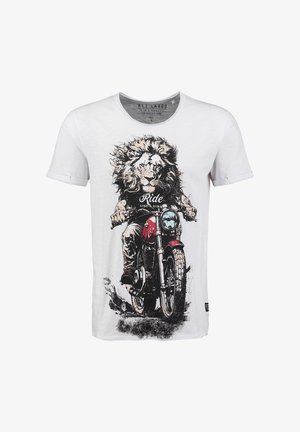 Wit T-shirt met een afbeelding van een leeuw die een rode motorfiets berijdt, tekst op het shirt luidt "Rij als een koning."