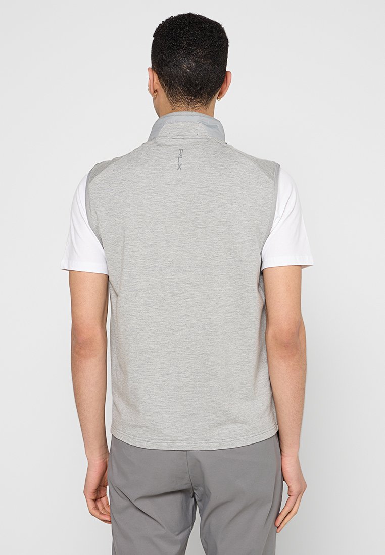 Chaleco sin mangas gris con cuello alto y detalles en gris claro, fabricado en una tela suave. Presenta un logo cerca del cuello y un diseño simple.