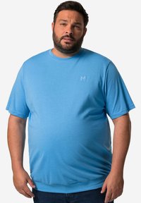 Modré tričko s krátkým rukávem vyrobené z měkké bavlněné tkaniny. Má kulatý výstřih a jemně vyšívané logo na hrudi.