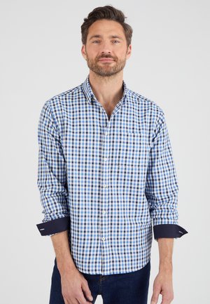 Camisa de cuadros en algodón azul y blanco con puños en navy y un bolsillo en el pecho. Presenta un cuello clásico y mangas largas.