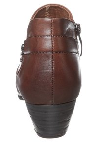Bottine en cuir marron avec un bout rond, dotée d'un talon haut, de détails piqués et d'une sangle avec boucle réglable sur le côté.