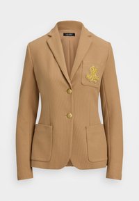 Blazer v barvě velbloudí s texturovanou tkaninou, s cípy na klopách, dvěma zlatými knoflíky a dekorativním zlatým vyšívaným logem na náprsním kapsy.