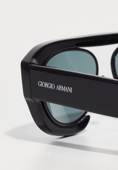 Ochelari de soare negri Giorgio Armani cu lentile colorate, văzuți din lateral. Numele mărcii este afișat proeminent pe ramă.