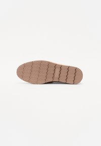 Talpă de sneaker din cauciuc de culoare maro deschis, cu un model de patern în zigzag, având o formă plată și o suprafață texturată pentru aderență și durabilitate.