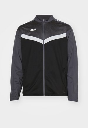 Schwarze und dunkelgraue Sportjacke mit hohem Kragen, Reißverschluss vorne und weißen Chevron-Details. Verfügt über strukturierten Stoff auf den Schultern.