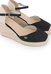 Espadrilles de cuña negras con parte superior de ante, suela de yute trenzado y correa de tela a rayas en el tobillo. Acento de logo en tono dorado en el costado.