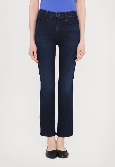 Jeans en denim bleu foncé avec une coupe droite, dotés de poches avant et d'une taille classique. Le tissu a une texture lisse sans ornementation.