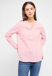 Himmelblause Hemd in hellrosa mit gepunktetem Muster, ausgestattet mit einem Henley-Ausschnitt, langen Ärmeln und legerem Schnitt. Der Stoff erscheint glatt und leicht.