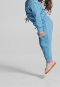 Hellblaues Sweatshirt und Hosen-Set mit lässigem Schnitt. Die Schuhe sind beige mit rosa Streifen und werden mit rosa karierten Socken kombiniert.