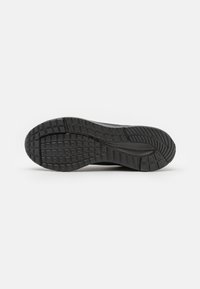 Black rubber shoe sole featuring a patterned tread for grip, with a smooth midsection and rounded edges.