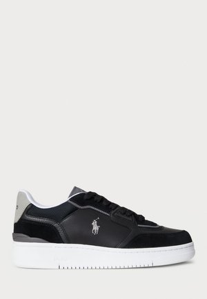 Black leather sneakers with a white rubber sole, featuring gray accents and logo detail. Smooth texture with contrast stitching.