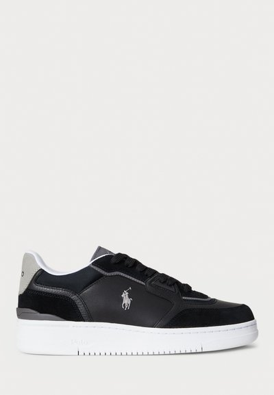 Baskets en cuir noir avec une semelle en caoutchouc blanc, présentant des accents gris et des détails de logo. Texture lisse avec couture contrastée.
