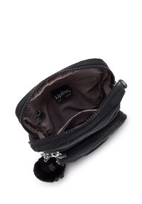 Black Kipling pouch featuring a zip closure, soft fabric exterior, and a furry pom-pom charm. Interior is lined in a smooth, light material.