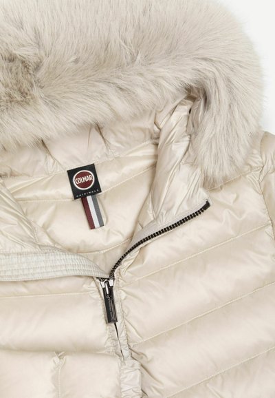 Doudoune beige avec fermeture éclair et capuche bordée de fausse fourrure beige clair, avec une étiquette noire Colmar Originals à l'intérieur du col.