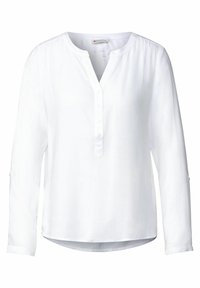 Camicia bianca a maniche lunghe con scollatura a fessura e patta con cinque bottoni. Realizzata in un tessuto liscio, presenta maniche arrotolabili con linguette per bottoni.